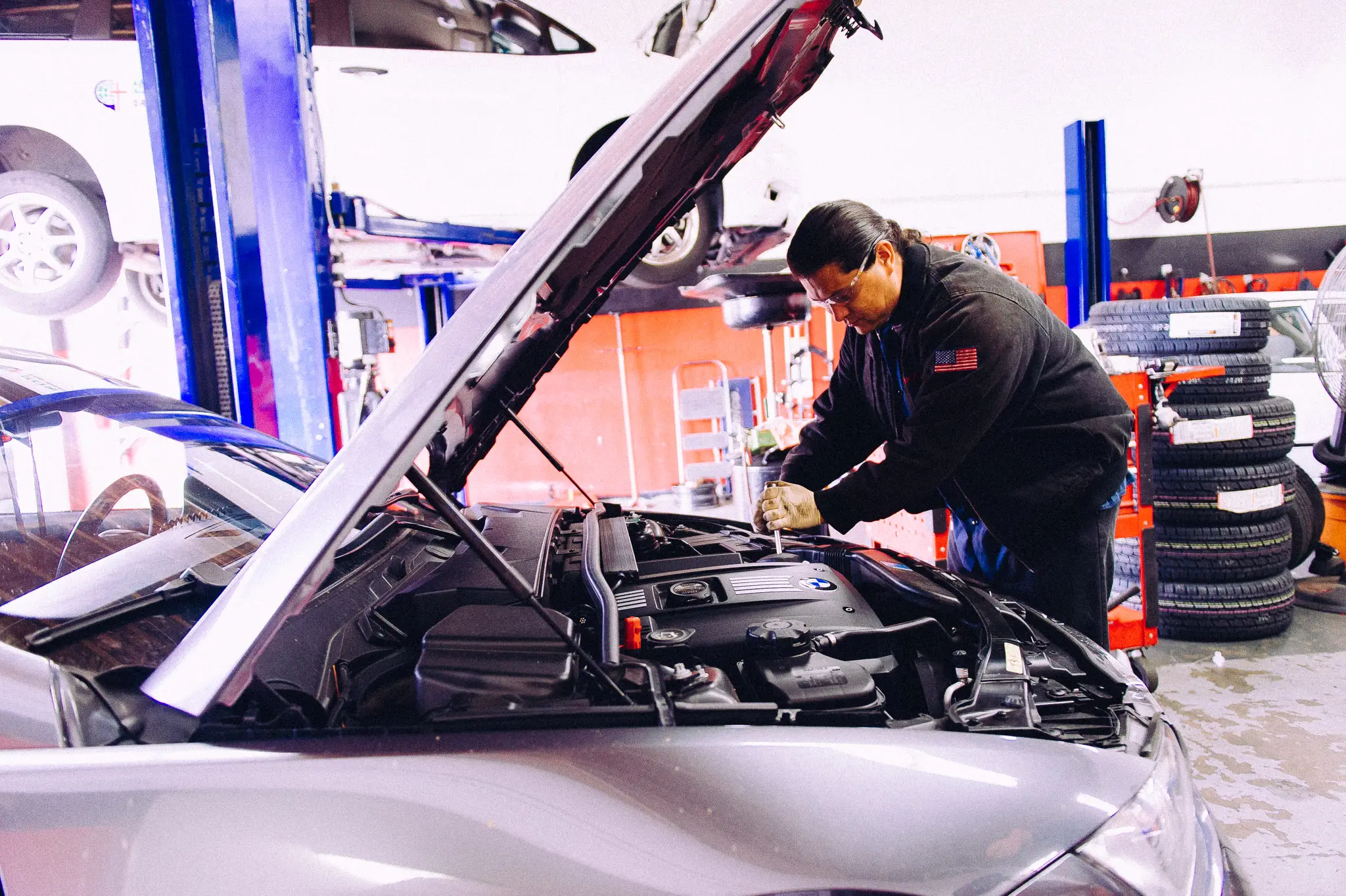 Mechanic performing engine work on a BMW sedan at SD Auto Medic